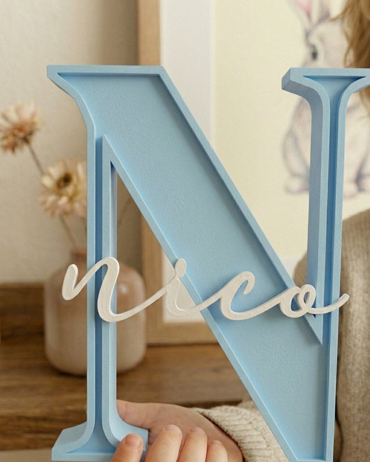 Inicial N azul cielo con el nombre Nico en la mano de un niño, para ver el tamaño
