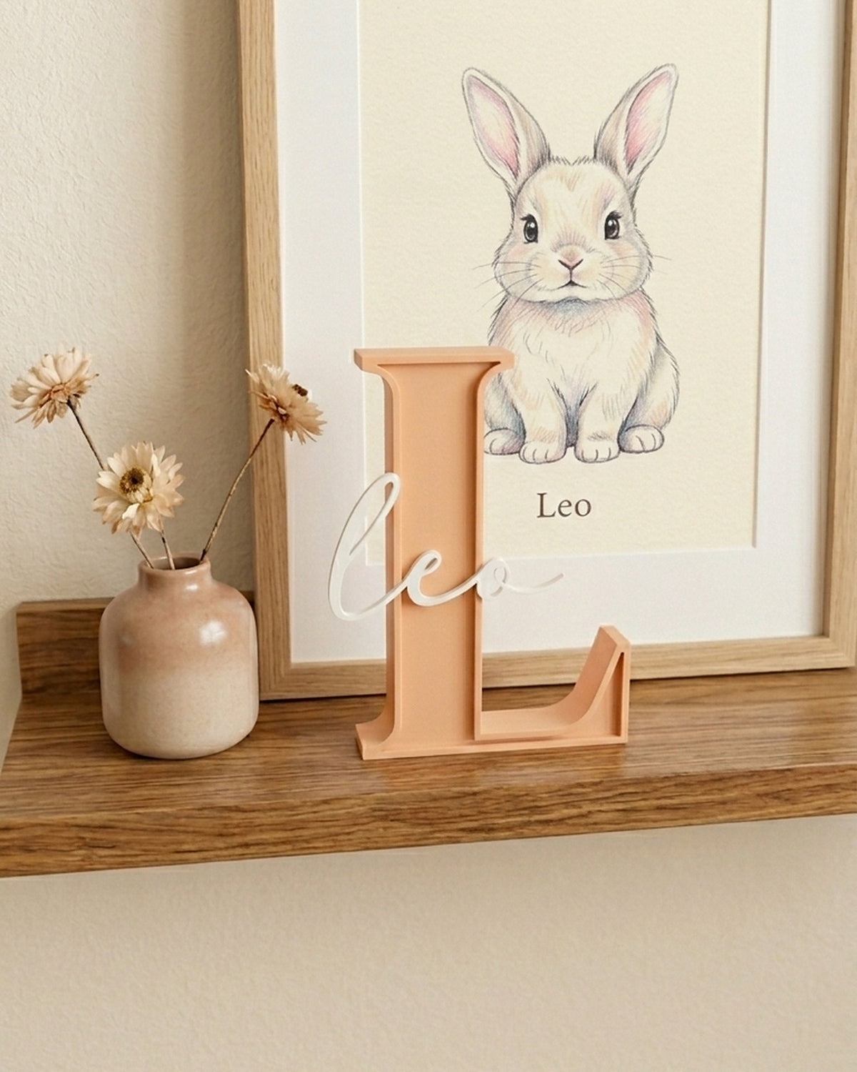 Letra L melocotón con el nombre Leo en la estantería de una habitación infantil